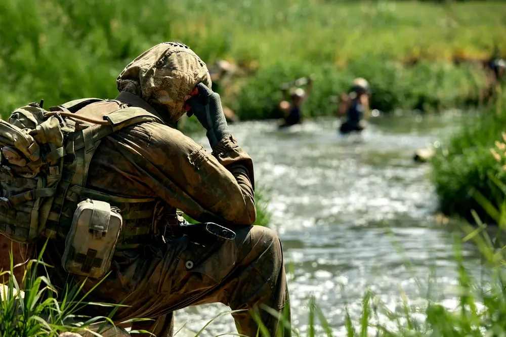 Instructeur militaire supervisant des soldats en formation lors d'un exercice de franchissement de rivière.