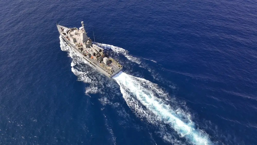 Vue aérienne d'un navire militaire de la marine naviguant en pleine mer lors d'une mission navale prolongée.