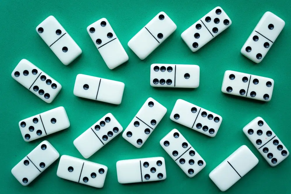 Des dominos en gros plan disposés sur un fond vert pour un exercice de suites logiques et de raisonnement abstrait.
