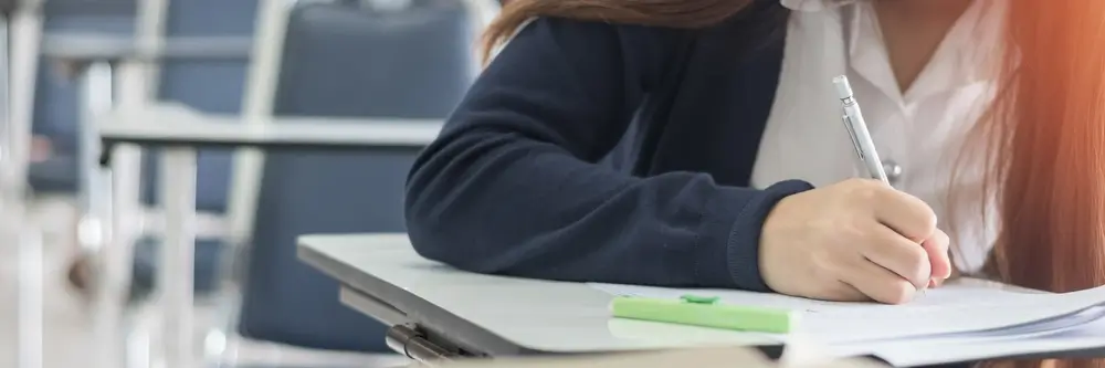 Candidate écrivant sur sa copie lors d'un test psychotechnique dans une salle d'examen.