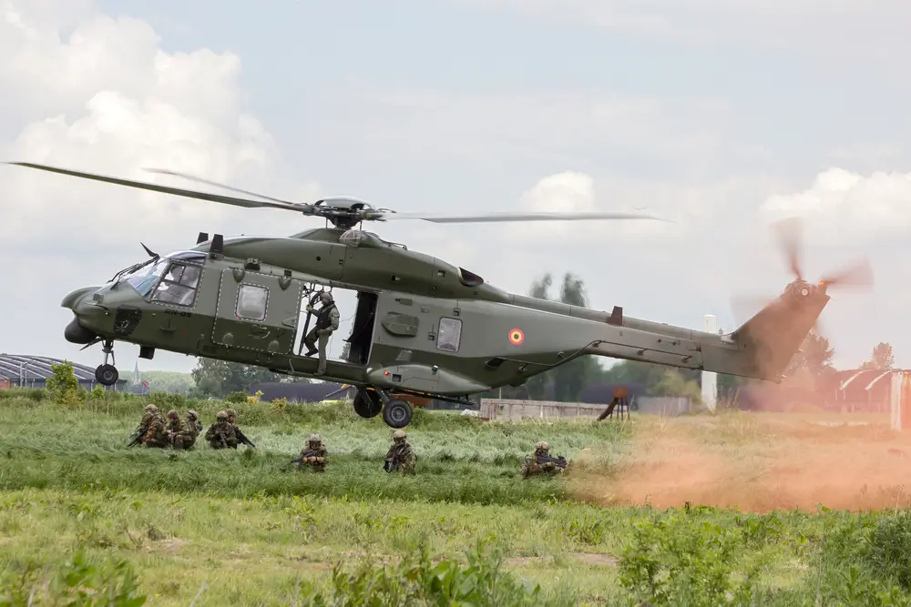 Commandos belges au béret vert en opération au sol avec un hélicoptère militaire NH90 lors d'une mission de l'armée.