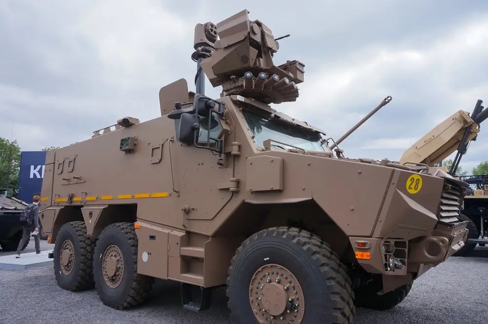 Véhicule militaire blindé Griffon brun à six roues et tourelle téléopérée, élément clé du programme belge CaMo.