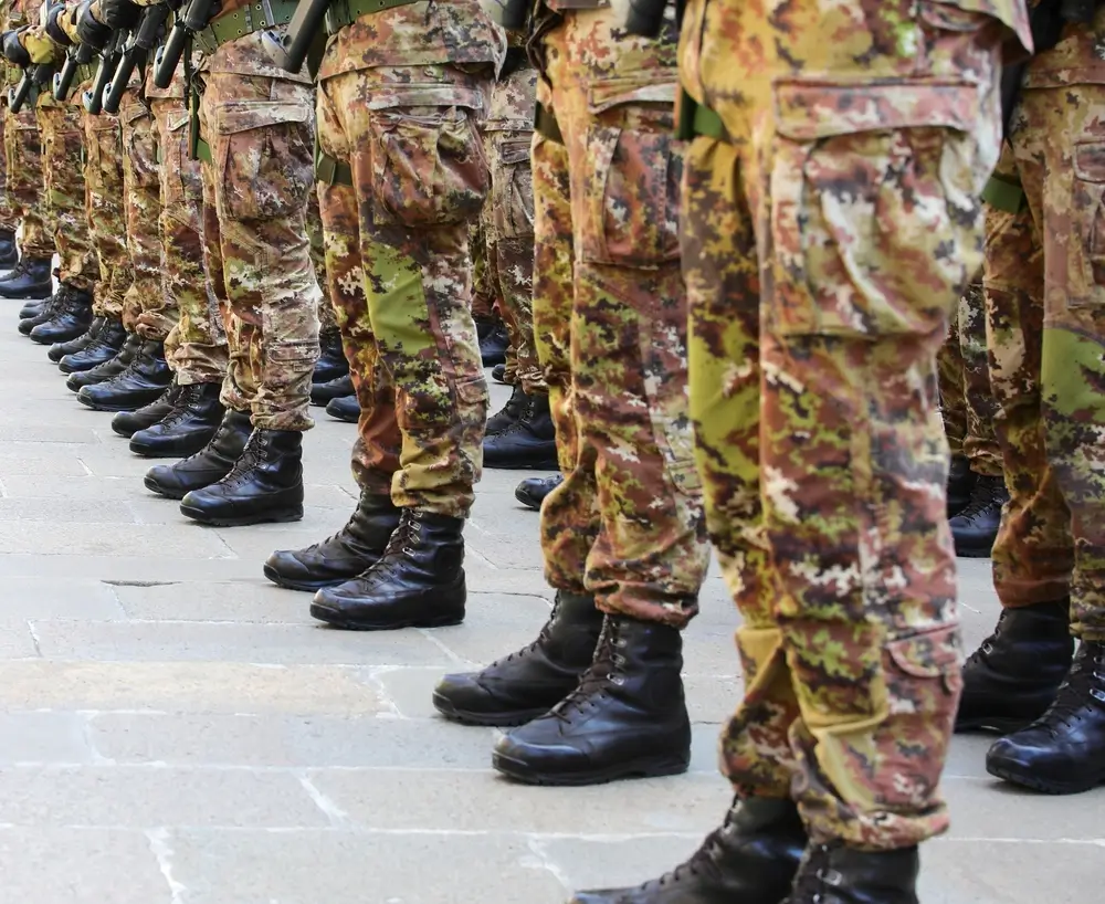 Recrues militaires en tenue de camouflage et bottes noires alignées pour une formation de soldats.