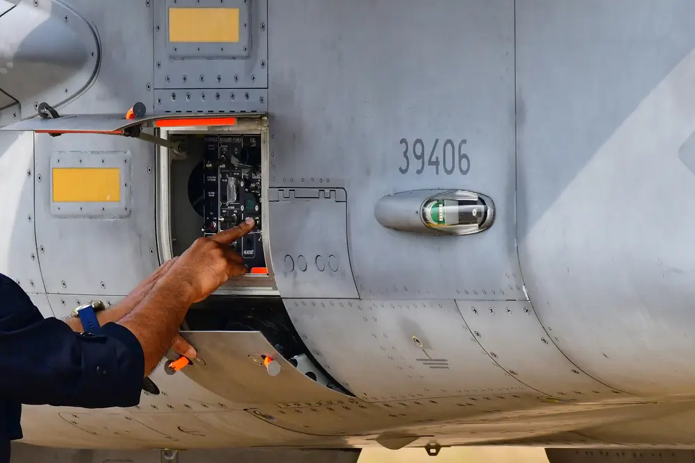 Technicien aéronautique militaire intervenant sur le panneau de commande d'un avion pour une maintenance technique.