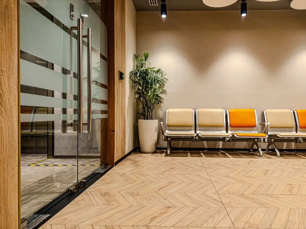 Salle d'attente moderne d'un centre de recrutement avec des sièges colorés, une porte vitrée et une plante.