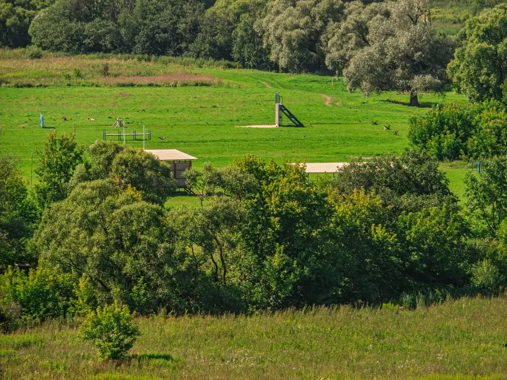 Terrain d'entraînement et infrastructures d'une base aérienne militaire entourés de verdure.