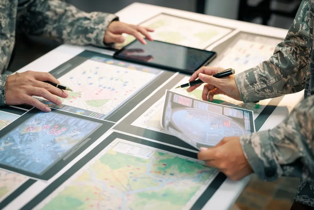 Officiers militaires analysant des cartes tactiques lors d'une séance d'instruction et de formation technique.